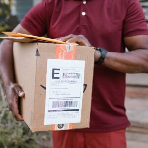 Close-up of a courier delivering a parcel with USPS express mail label outdoors.